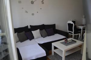 Sala de estar con sofá en blanco y negro y mesa en Apartman Rada, en Bijeljina