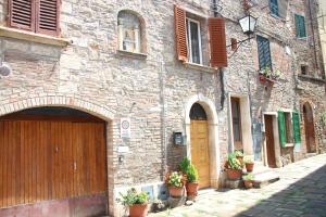 un bâtiment en pierre avec une porte en bois et des plantes en pot dans l'établissement Carolina Apartment, à Rapolano Terme