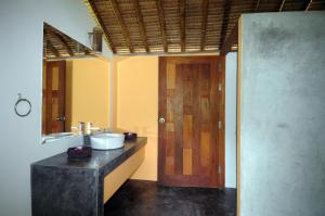 a bathroom with a sink and a wooden door at Koh Yao Sunrise Villa in Ko Yao Noi