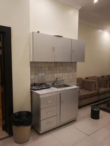 a kitchen with a sink and a stove and a couch at Saad Palace Residential Units - Al Rabwa 2 in Abha
