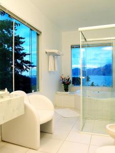 a white bathroom with a glass shower and a tub at Hotel Itapemar - Ilhabela in Ilhabela