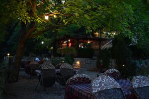 a restaurant with tables and chairs under a tree at Hotel Vila Ivanković in Buna