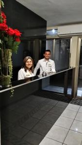 a man and a woman standing at a counter at Hotel San Jose Hostal in San Salvador
