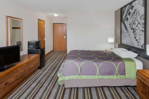 a hotel room with a bed and a flat screen tv at Super 8 by Wyndham Gilman in Gilman