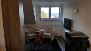 een kamer met 2 stoelen, een tafel en een raam bij Room with a High Tatras view and Fireplace in Štrba