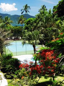 a resort with a pool and palm trees and flowers at Hotel Itapemar - Ilhabela in Ilhabela