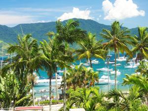a group of palm trees and boats in a harbor at Hotel Itapemar - Ilhabela in Ilhabela