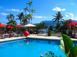 a swimming pool with chairs and umbrellas at Hotel Itapemar - Ilhabela in Ilhabela