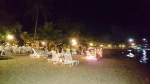 a group of people standing around a fire on the beach at night at Hotel Itapemar - Ilhabela in Ilhabela