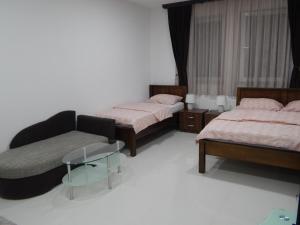 a room with three beds and a couch and a chair at Apartments S&S in Konjic