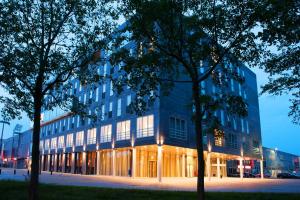 een groot glazen gebouw met bomen ervoor bij Hotel Lumen Zwolle in Zwolle