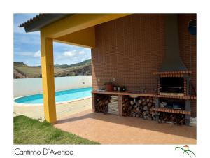 uma cozinha exterior com lareira ao lado de uma piscina em Cantinho D'Avenida em Velas