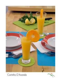 Dois copos de sumo de laranja sentados numa mesa. em Cantinho D'Avenida em Velas