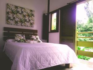 1 dormitorio con 1 cama con manta rosa y ventana en Nalu Guest House, en Ubatuba