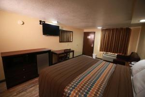 Memphis Inn في ممفيس: غرفة فندقية فيها سرير ومكتب وتلفزيون
