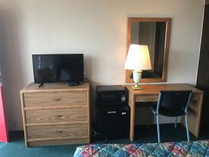 a bedroom with a desk with a television and a dresser at Budget Host Village Inn in Kirksville