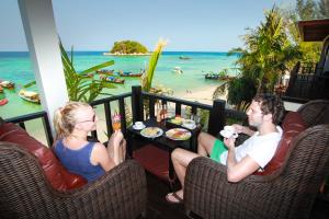 Ein Mann und eine Frau sitzen an einem Tisch auf einem Balkon mit Strand in der Unterkunft Cabana Lipe Beach Resort in Ko Lipe