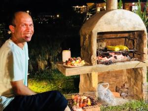 un uomo seduto di fronte a un forno all'aperto di Country Retreat a Mae Rim