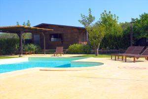 a swimming pool with two benches and a house at Agriturismo Mammarella in Altavilla Silentina