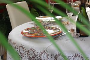 ラヴァーニャにあるHotel Albaの白いテーブルクロスに皿とメガネをかけたテーブル
