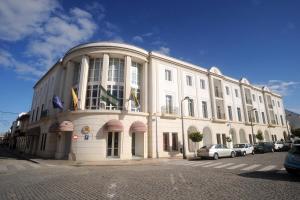 a large white building with cars parked in front of it at Hotel Castillo in Palma del Río