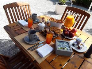 - une table en bois avec de la nourriture pour le petit-déjeuner et du jus d'orange dans l'établissement Le Clos Notre Dame, à Montlouis-sur-Loire