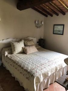 1 dormitorio con 1 cama con edredón blanco en La Casa del Tatone, en Gambassi Terme