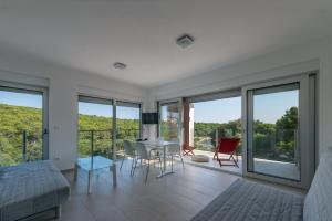 a living room with a table and chairs and windows at Premantura Resort - Hotel & Restaurant in Premantura