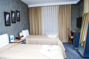 a hotel room with two beds and a television at Bergs Hotel And Restaurant in Qax +30 photos