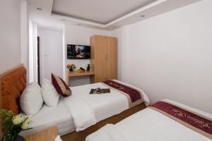 two beds in a room with white walls at Hanoi Fantasea Hotel in Hanoi