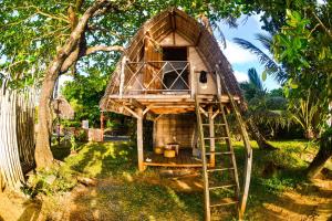 a tree house with a ladder in a yard at Chez Nath in Sainte Marie