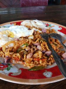 a plate of food with noodles and eggs on a table at Yulia Resort in Sabang