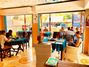 a group of people sitting at tables in a restaurant at Lembongan Tropical Guesthouse in Nusa Lembongan