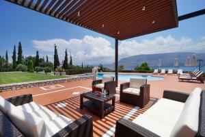 an outdoor patio with white furniture and a swimming pool at Villa Thealassa in Kounoupidhianá