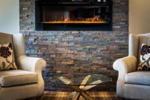 a living room with two chairs and a fireplace at Kinloch Hotel, Isle of Arran in Blackwaterfoot