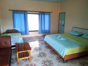 een slaapkamer met 2 bedden en een raam met blauwe gordijnen bij Peace Pool Resort in Khun Han