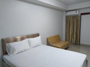 Roseate Bangkok Hotel في بانكوك: غرفة نوم بسرير ابيض وكرسي