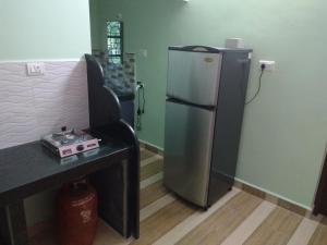 a kitchen with a refrigerator next to a table at The Purple House in Agonda