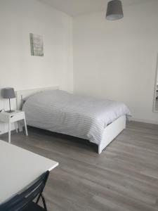 ein weißes Schlafzimmer mit einem Bett und einem Tisch in der Unterkunft Appart Hôtel L'Angélique in Saint-Nazaire