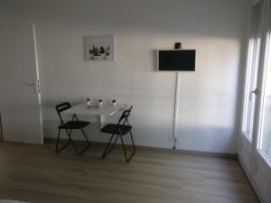 ein weißes Zimmer mit einem Tisch und 2 Stühlen in der Unterkunft Appart Hôtel L'Angélique in Saint-Nazaire