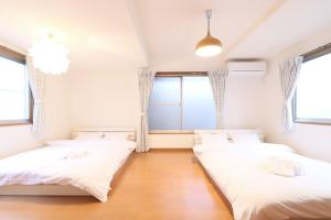 two beds in a room with two windows at Tokaichi inn 一軒家貸切 in Hiroshima