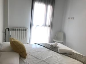 una camera da letto bianca con un letto e asciugamani di VTZ El Balcón del Coso II a Saragozza