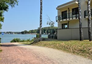 a house on the side of a road next to a lake at Apartament plażowy Ukiel in Olsztyn