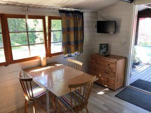 a dining room with a table and chairs and a television at Smedens Stugby in Smedjebacken