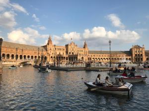 people in canoes in the water in front of a large building at Tavira Apartment in Tavira