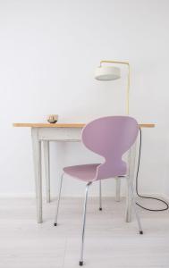 uma cadeira rosa sentada ao lado de uma mesa branca em Kunstart20 em Saltum