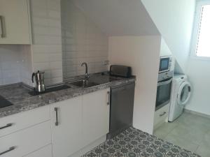 a kitchen with a sink and a washing machine at Chalet con dos apartamentos in La Azohía