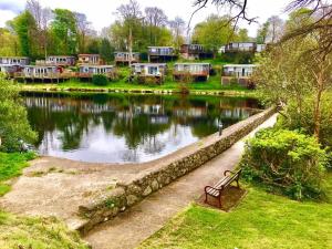 a park bench next to a lake with houses at Cozy Snowdonia Chalet in Caernarfon