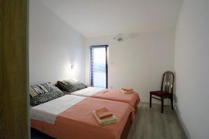 - une chambre avec deux lits, une chaise et une fenêtre dans l'établissement Dalmatian, à Bilice