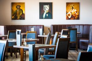 a dining room with tables and chairs and paintings on the wall at Kinloch Hotel, Isle of Arran in Blackwaterfoot